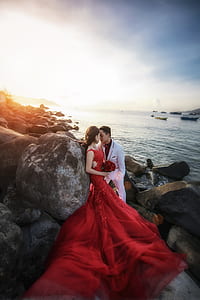 woman wearing red dress beside man wearing suit jacket surrounded by rocks thumbnail