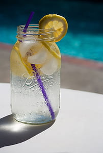 selective focus photography of clear glass mason jar with lemonade and purple straw thumbnail