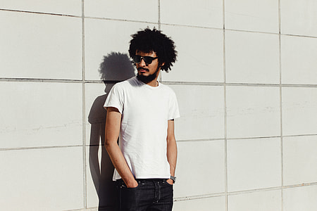 standing man near concrete wall wearing white crew-neck t-shirt, black denim jeans and black wayfarer-style sunglasses near during daytime thumbnail