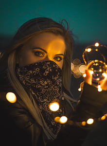 selective focus photo of woman wearing blue and white floral mask taken at nighttime thumbnail