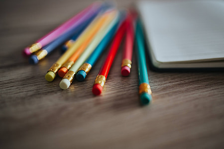 Notebooks with colourful pencils on a wooden desk thumbnail