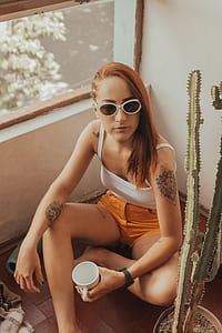 woman sitting on floor near white wall beside glass window thumbnail