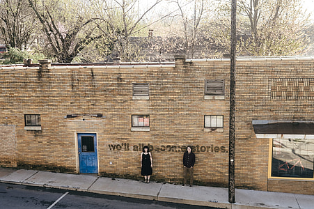 man and woman standing behind wall thumbnail