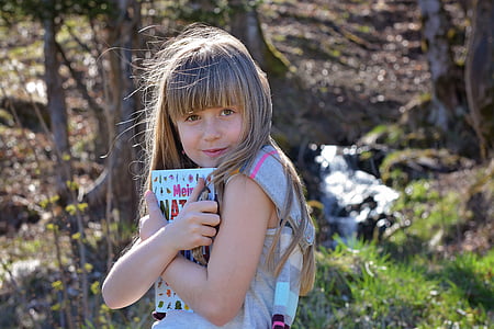 girl hugging book during daytime thumbnail