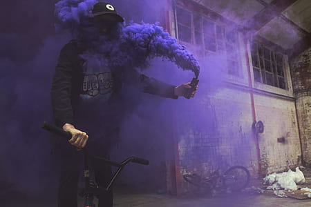 person riding BMX bike while holding black smoke bottle inside building thumbnail