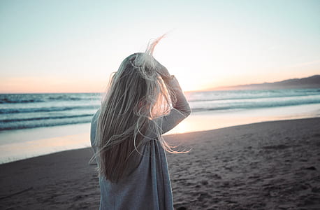 woman walking on the shore during daytime thumbnail