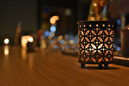 selective-focus photo of lighted candle in black candle holder on brown wooden surface thumbnail