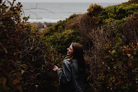 woman standing between grass plant near shoreline thumbnail