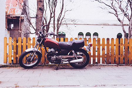 red cruiser motorcycle parked beside wooden fence thumbnail