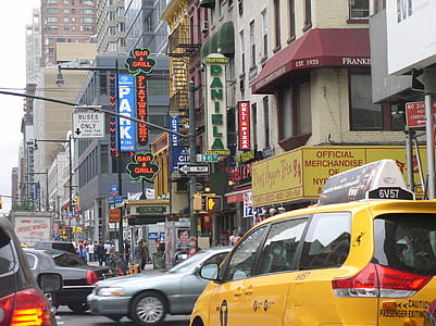 people walking on sidewalk beside road with vehicles and during daytime thumbnail