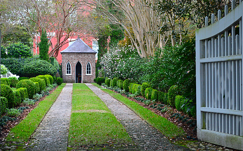 pathway between green leafed trees in front of brown and gray house during daytime thumbnail