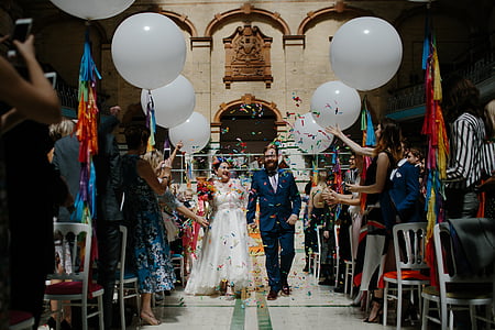 married couple walking towards with confetti falling between the crowd at daytime thumbnail