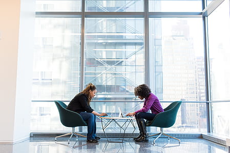 Two Woman Sitting Near Green Padded Chair thumbnail