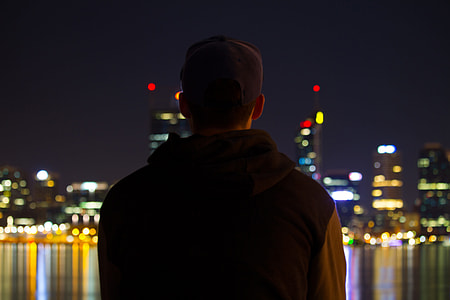A man sitting at night looking at the city lights thumbnail