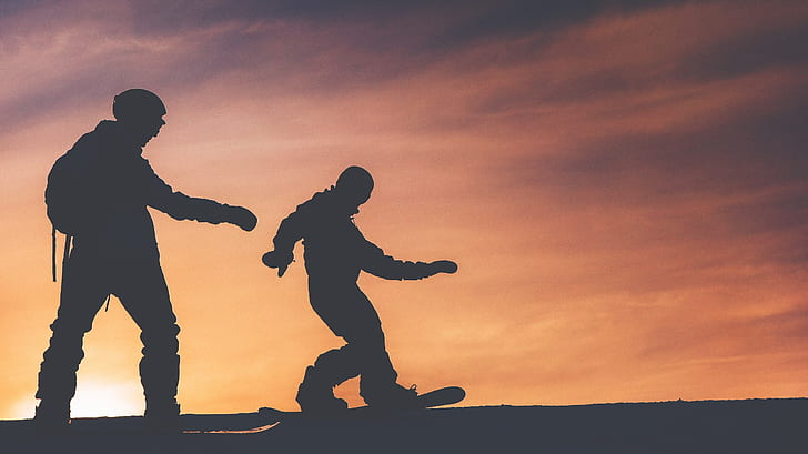 silhouette of two men skiing