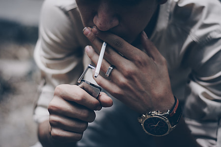 person with cigarette on mouth near flip lighter thumbnail