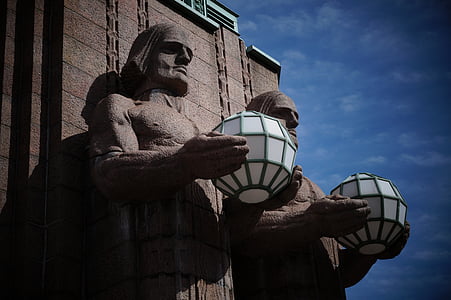 two concrete men statues holding white and green container during daytime thumbnail