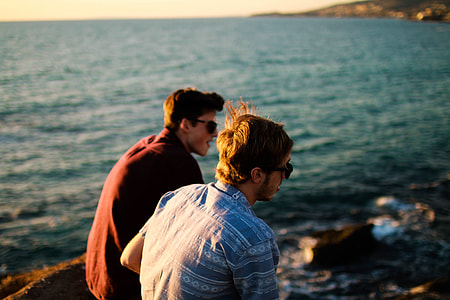 two man wearing black sunglasses beside on body of water during daytime thumbnail