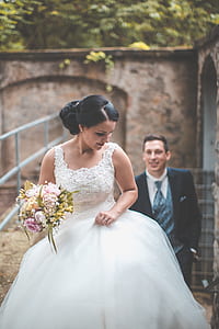 selective focus photography of woman wearing white wedding dress walking on pathway thumbnail