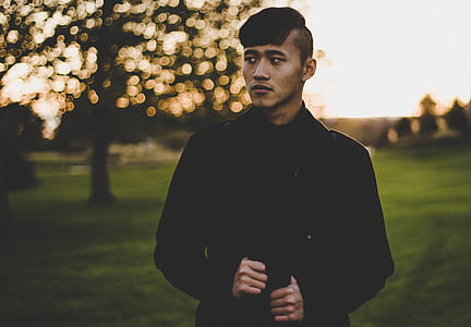 man in black jacket standing on green grass thumbnail