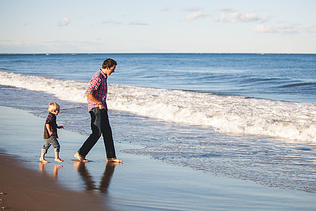 man with boy walking in seashore during day time thumbnail