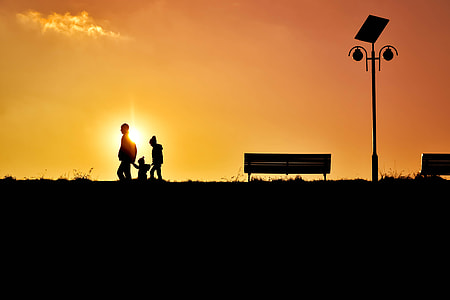 silhouette of three person walking near bench and post at sunset thumbnail
