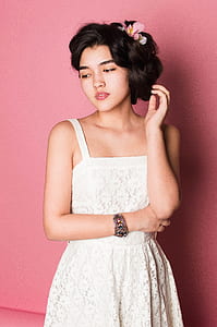 woman wearing white shirt standing near pink wall thumbnail