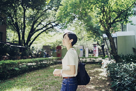 woman in white blouse standing near trees thumbnail
