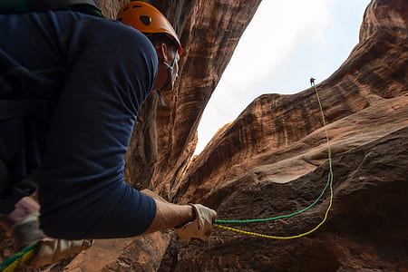 low angle view of man under cliff holding rope thumbnail