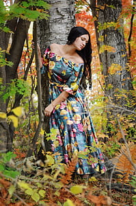 woman wearing blue and yellow floral off-shoulder maxi dress standing beside green tree thumbnail