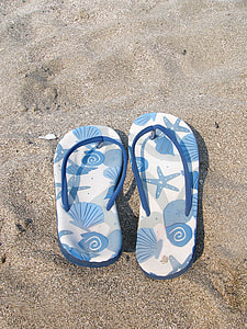 pair of white-and-blue starfish print flip-flops on gray sand thumbnail