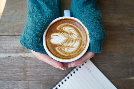 person holding cup with coffee art thumbnail
