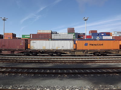red, white and orange shipment container beside railways thumbnail