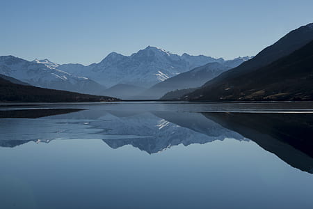 grey calm body of water near snow covered mountains at daytime thumbnail