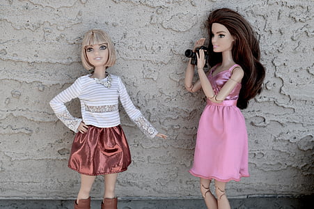photo of two Barbie dolls near white concrete wall thumbnail