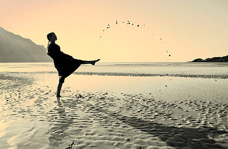 person raising right foot standing on seashore thumbnail