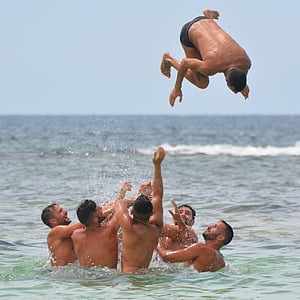 group of topless men in body of water under blue sky during daytime thumbnail