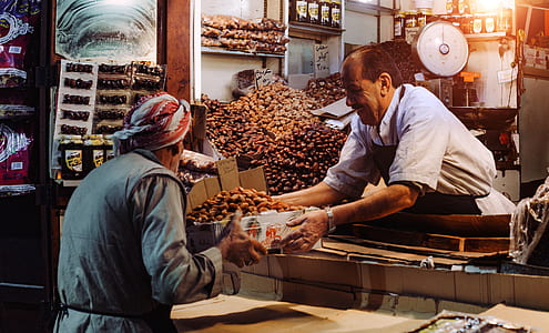 Man in Blue Top Giving Box to Man in Gray Top thumbnail
