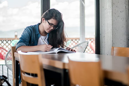 woman sitting down at table writing down on paper thumbnail