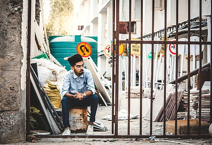 man sitting on white can near open gate thumbnail