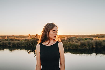 woman in black tank top standing near calm body of water thumbnail