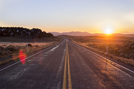 gray concrete straight road under blue sky at sunset thumbnail