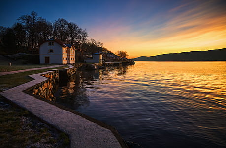 white concrete house near body of calm water during golden hour thumbnail
