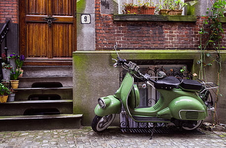green motor scooter parked on roadside thumbnail