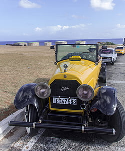 vintage yellow car parked near body of water thumbnail