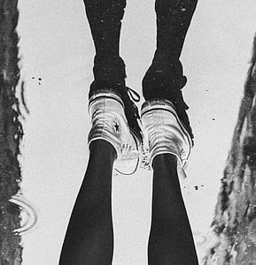 grayscale photo of person wearing All Star Converse high-top shoes thumbnail