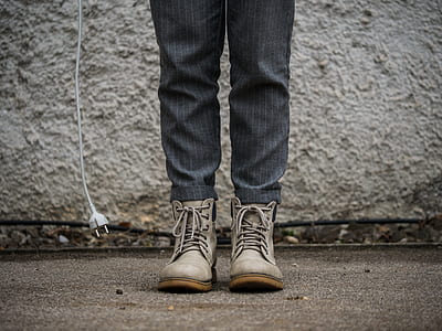 person wearing gray boots standing near white wall thumbnail