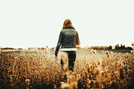 Woman in Blue Denim Jacket Walking on Field thumbnail