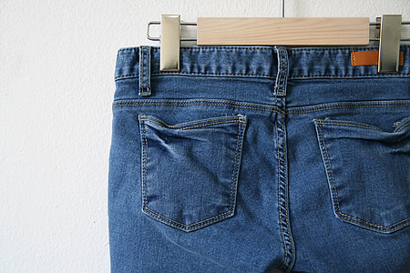 blue denim bottoms hanged on wooden hanger in close-up photography thumbnail