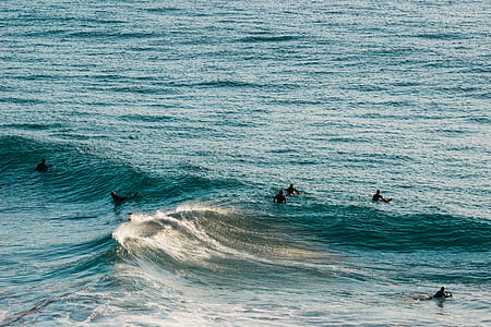 six people waiting at waves on body of water thumbnail